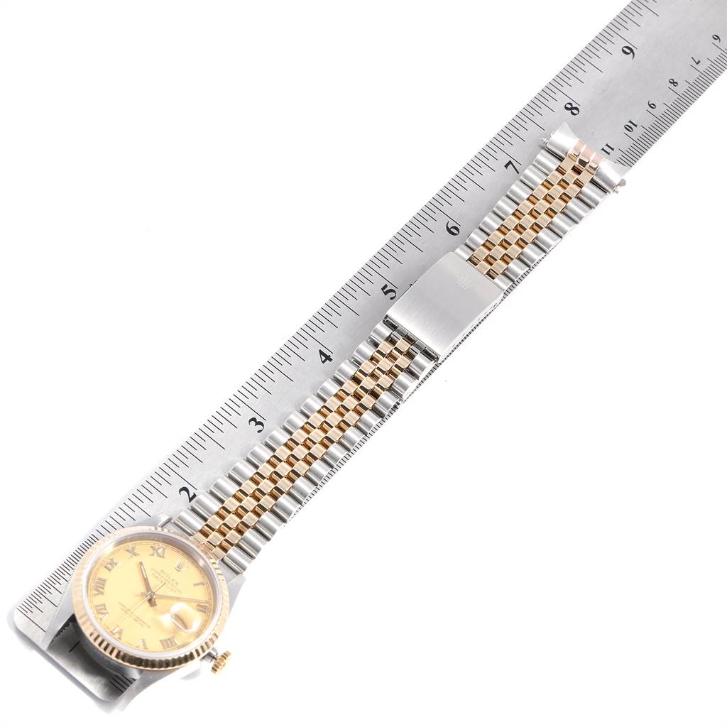 The Rolex Datejust 16233 Men
s Steel and Gold (two tone) Champagne Dial 16233 Men
s Steel and Gold (two tone) Champagne Dial watch is shown from a top-down angle, displaying the face, bracelet, and part of a ruler for measurement.