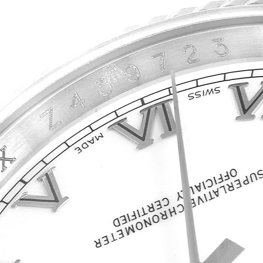 This close-up image of a Rolex Datejust 116234 Men's Stainless Steel White Dial 116234 Men's Stainless Steel White Dial watch captures part of the dial, including Roman numerals, text, and part of the serial number on the inner bezel.