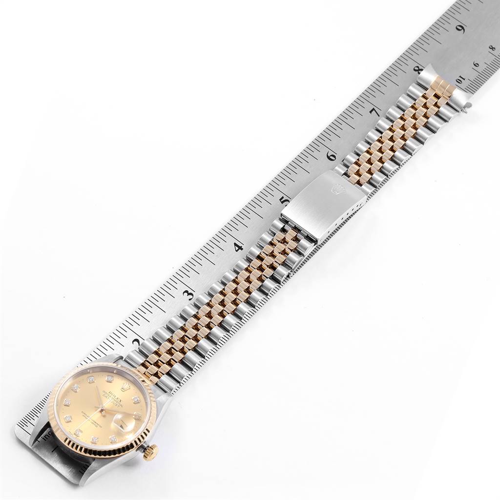 This image shows a Rolex Datejust 16233 Men
s Steel and Gold (two tone) Champagne Dial 16233 Men
s Steel and Gold (two tone) Champagne Dial watch and its two-tone bracelet alongside a ruler for measurement.