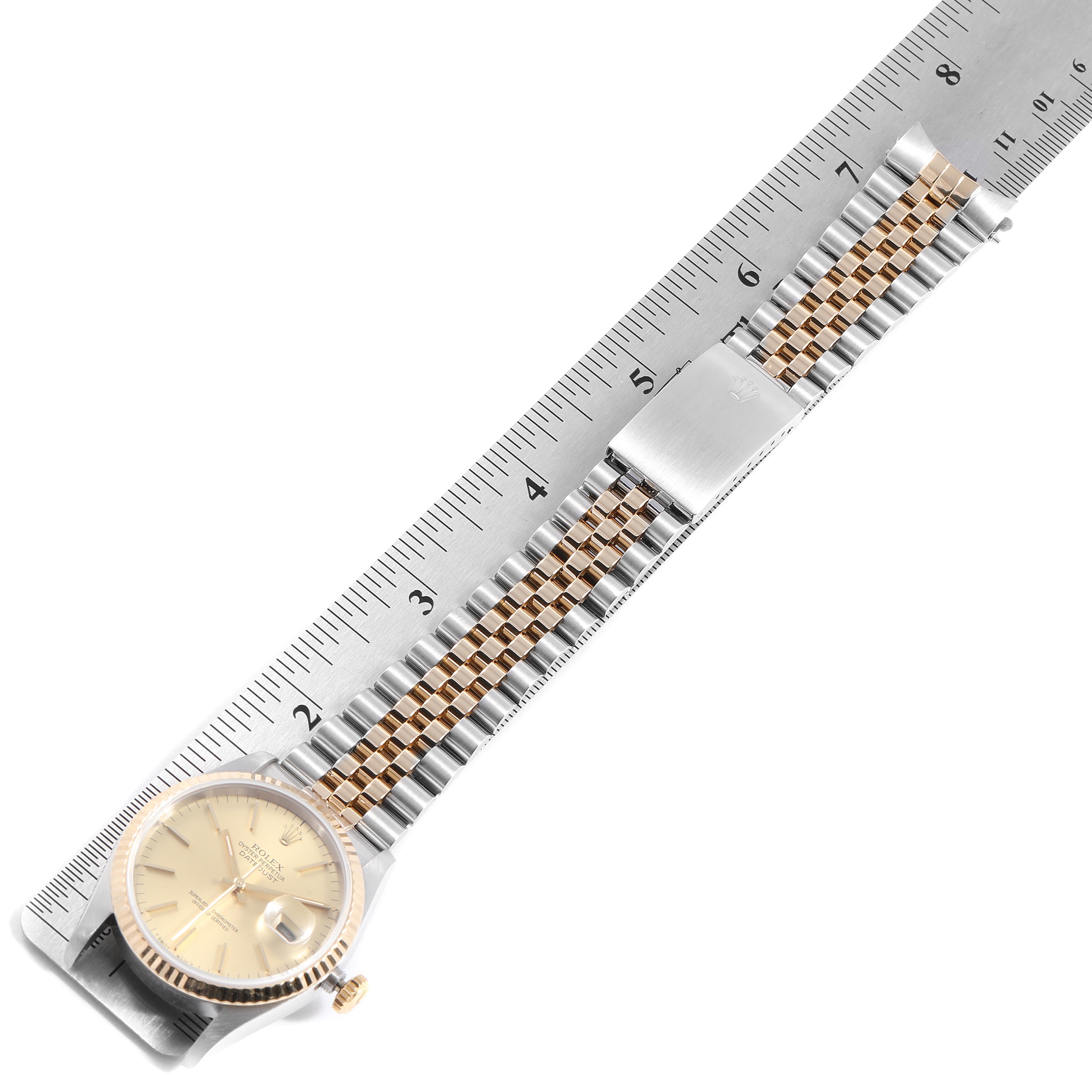The image shows a Rolex Datejust 16233 Men's Steel and Gold (two tone) Champagne Dial 16233 Men's Steel and Gold (two tone) Champagne Dial watch laid flat next to a ruler, highlighting its dial and bracelet.