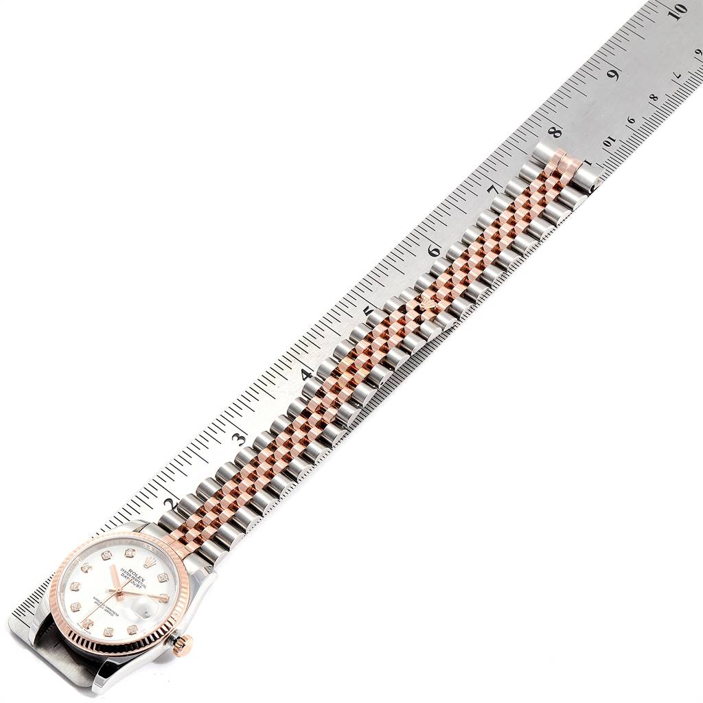 The Rolex Datejust 116231 Men
s Steel and Gold (two tone) White Dial 116231 Men
s Steel and Gold (two tone) White Dial watch is shown from an aerial angle, displaying its face, bezel, crown, and bracelet alongside a ruler.