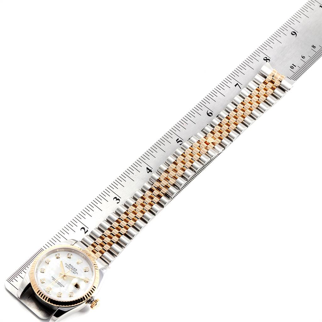 The image shows the Rolex Datejust 116233 Men's Stainless Steel Mother of Pearl Dial 116233 Men's Stainless Steel Mother of Pearl Dial watch laid flat with its dial and bracelet next to a ruler.