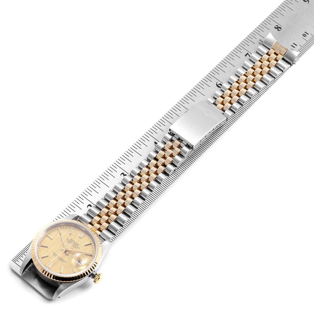 The image shows a top view of a Rolex Datejust 16233 Men's Steel and Gold (two tone) Champagne Dial 16233 Men's Steel and Gold (two tone) Champagne Dial watch with a two-tone bracelet placed on a ruler.