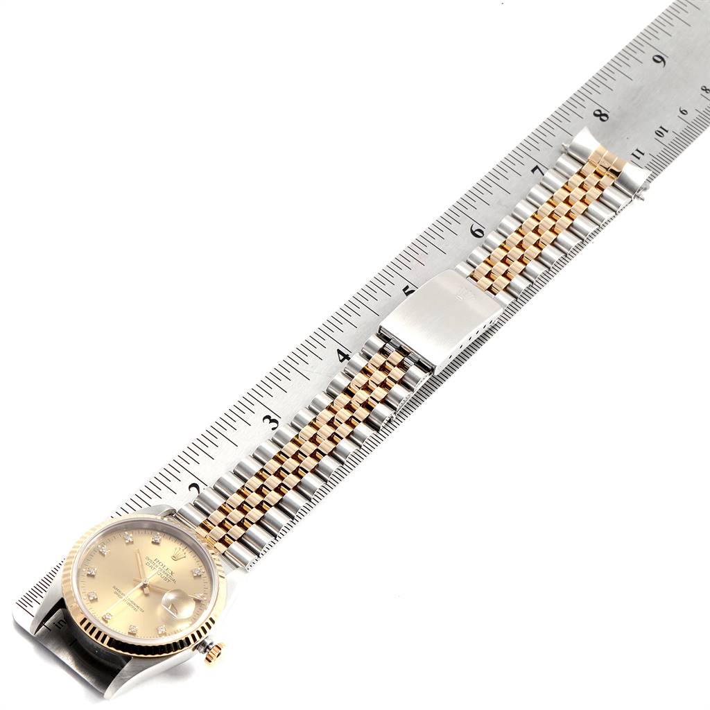 This image shows a Rolex Datejust 16233 Men's Steel and Gold (two tone) Champagne Dial 16233 Men's Steel and Gold (two tone) Champagne Dial watch laid flat with its two-tone bracelet placed next to a ruler for scale.