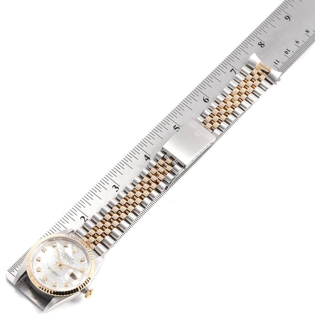 The image shows a Rolex Datejust 16233 Men's Steel and Gold (two tone) Mother of Pearl Dial 16233 Men's Steel and Gold (two tone) Mother of Pearl Dial watch laid flat on a ruler, displaying its dial, bracelet, and clasp from a top-down angle.