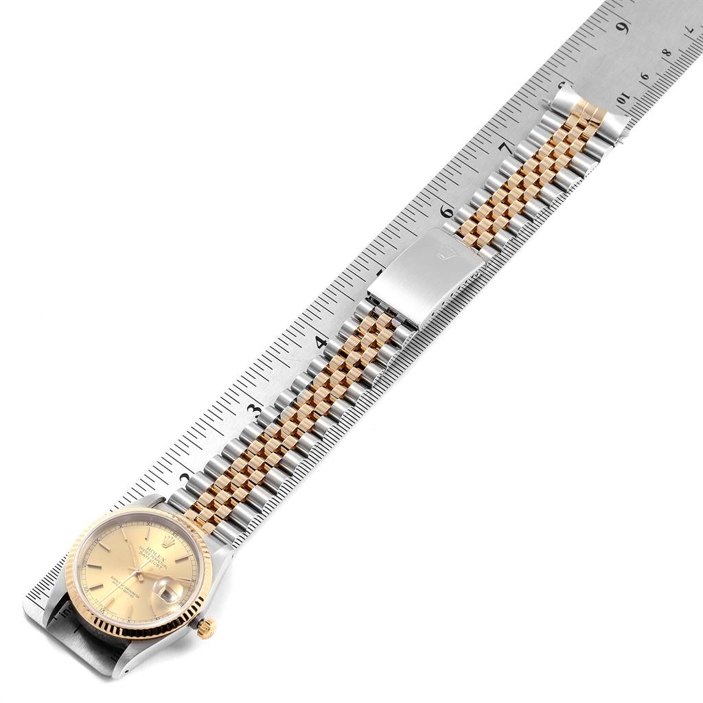 The image shows a top-down view of a Rolex Datejust 16233 Men's Steel and Gold (two tone) Champagne Dial 16233 Men's Steel and Gold (two tone) Champagne Dial watch, highlighting its dial, bezel, bracelet, and clasp against a ruler.