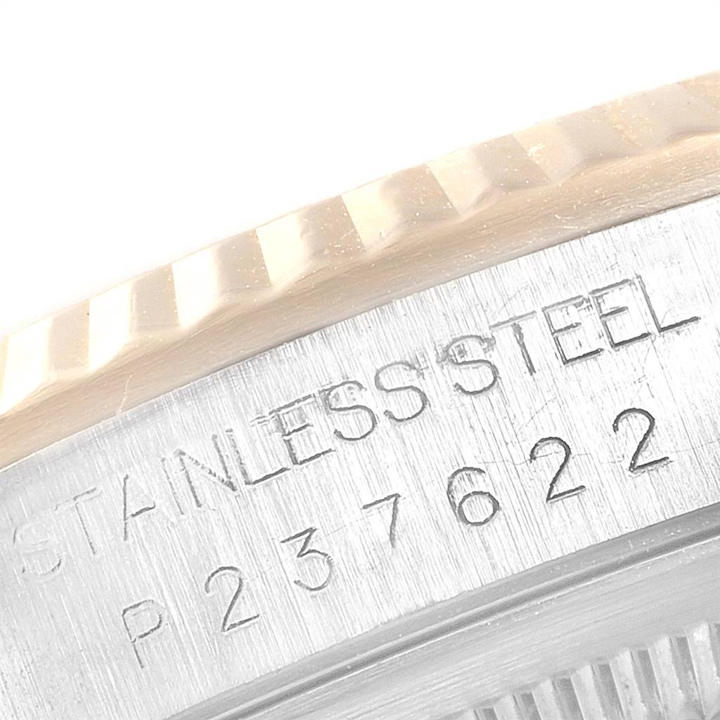 This close-up image of a Rolex Datejust 16233 Men's Steel and Gold (two tone) Mother of Pearl Dial 16233 Men's Steel and Gold (two tone) Mother of Pearl Dial watch shows the fluted bezel and part of the case with engraved serial numbers.