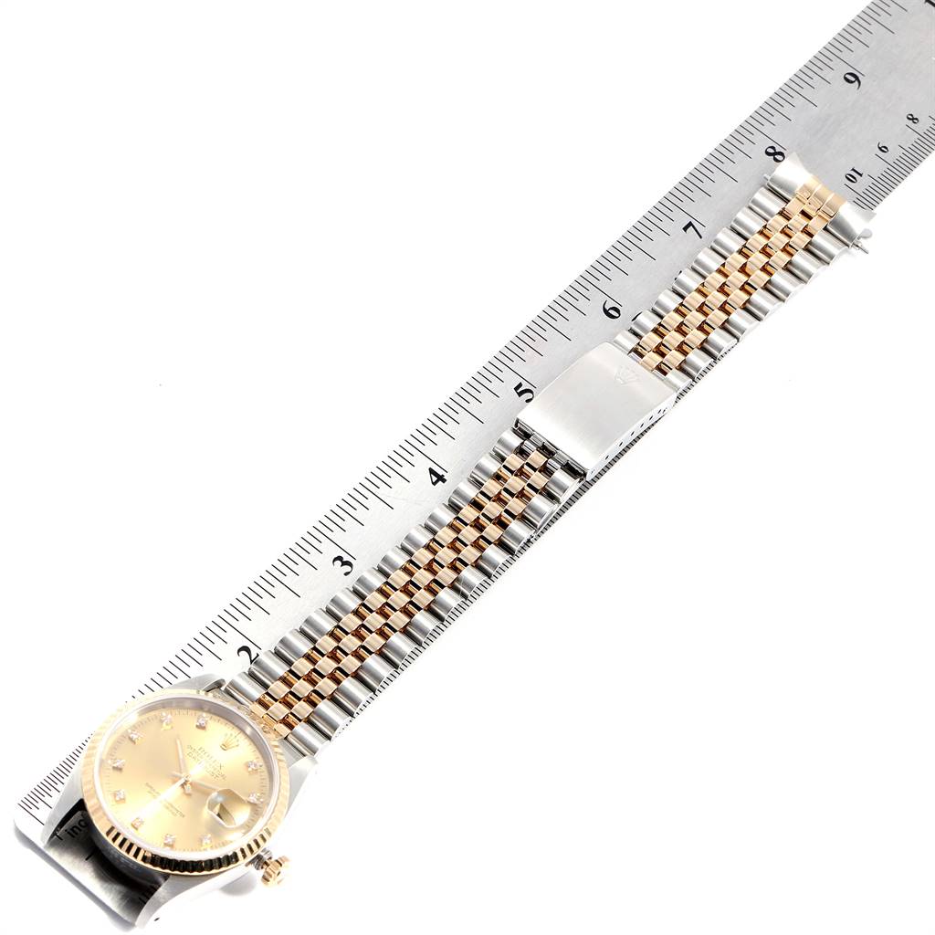 The image shows a Rolex Datejust 16233 Men's Steel and Gold (two tone) Champagne Dial 16233 Men's Steel and Gold (two tone) Champagne Dial watch placed alongside a ruler, highlighting its gold and silver bracelet and face.