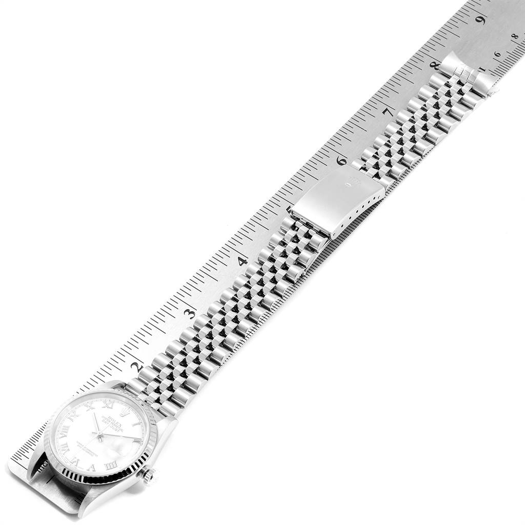 The Rolex Datejust 16234 Men's Stainless Steel White Dial 16234 Men's Stainless Steel White Dial watch is photographed from above, showing the face, bracelet, and clasp against a ruler backdrop.