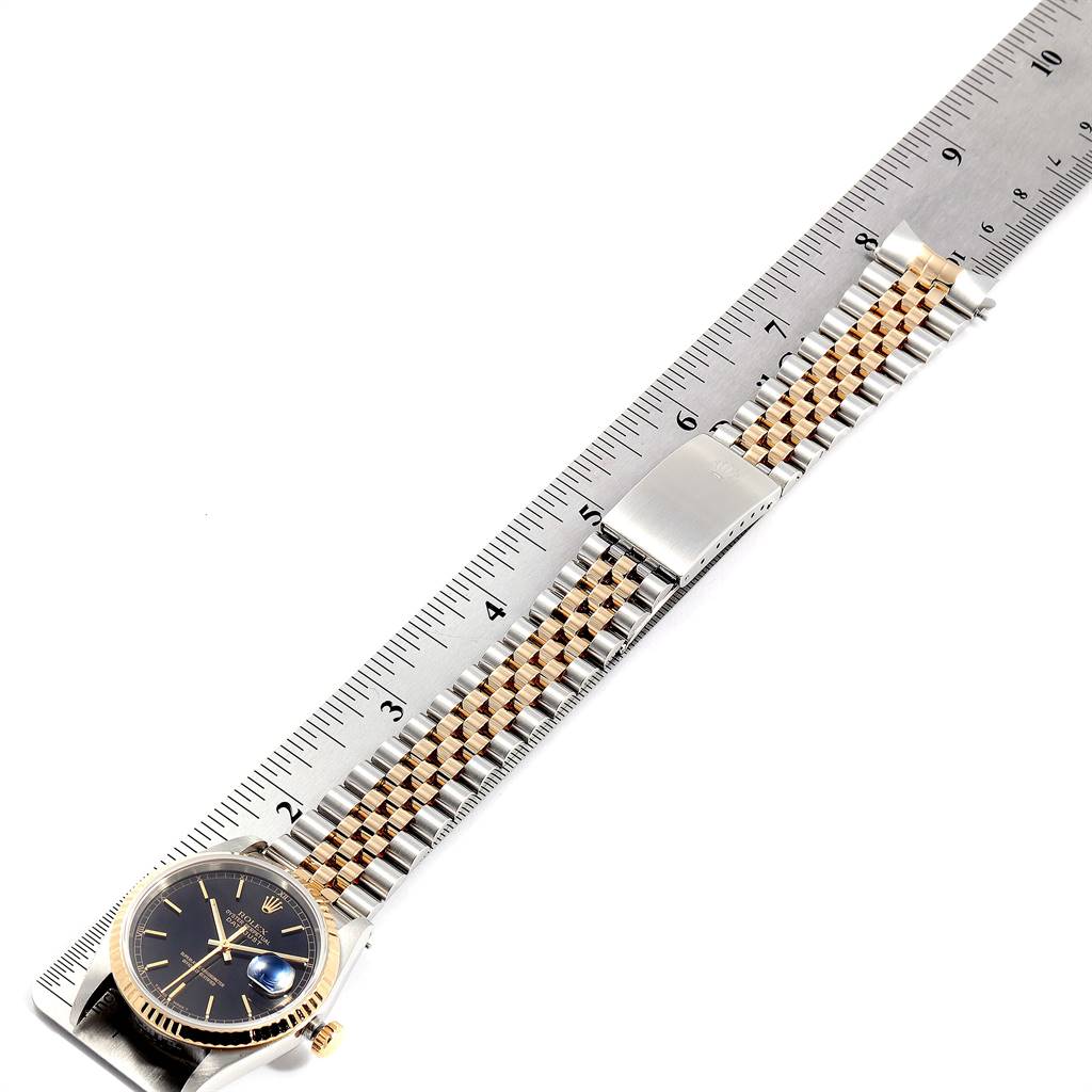 The image shows a Rolex Datejust 16233 Men
s Steel and Gold (two tone) Black Dial 16233 Men
s Steel and Gold (two tone) Black Dial watch, including the dial, bracelet, and clasp, measured next to a ruler.