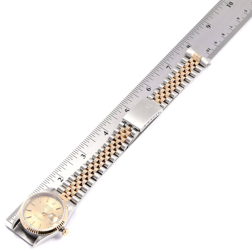 The Rolex Datejust 16233 Men
s Steel and Gold (two tone) Champagne Dial 16233 Men
s Steel and Gold (two tone) Champagne Dial watch is displayed flat, showing the face, crown, and entire metal bracelet beside a ruler for scale.