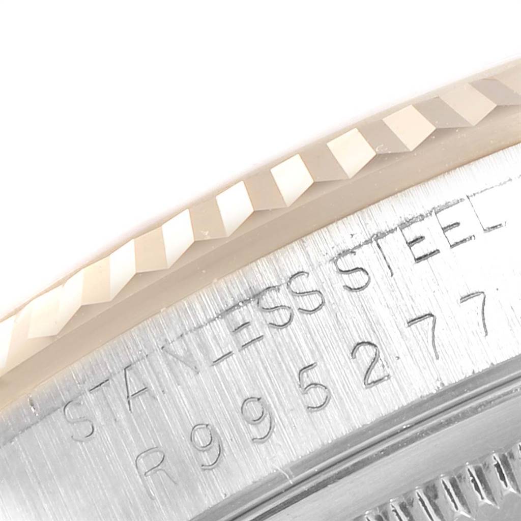 This image shows a close-up of the stainless steel flange and fluted bezel of a Rolex Datejust 16233 Men's Steel and Gold (two tone) Champagne Dial 16233 Men's Steel and Gold (two tone) Champagne Dial watch, highlighting engraved text.