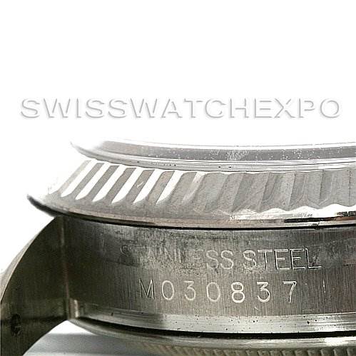 This image shows a close-up side view of a Rolex Datejust 116234BKRSJ Men's Stainless Steel Silver Dial 116234BKRSJ Men's Stainless Steel Silver Dial watch, displaying the fluted bezel and part of the case with engraving.