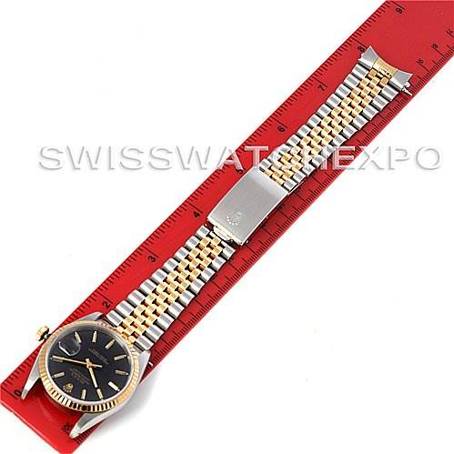 A Rolex Datejust 16233 Men's Steel and Gold (two tone) Black Dial 16233 Men's Steel and Gold (two tone) Black Dial watch is displayed flat, showcasing the entire bracelet and dial, measured against a red ruler.