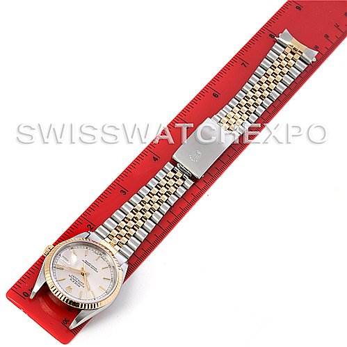 This is an overhead view of a Rolex Datejust 16233 Men's Steel and Gold (two tone) Silver Dial 16233 Men's Steel and Gold (two tone) Silver Dial watch, showing the entire watch including the face, bezel, and bracelet laid next to a ruler.