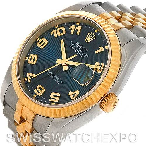The image shows a Rolex Datejust 116233 Men
s Stainless Steel Blue Dial 116233 Men
s Stainless Steel Blue Dial watch at an oblique angle, highlighting its two-tone bracelet, gold bezel, and blue dial with Arabic numerals.