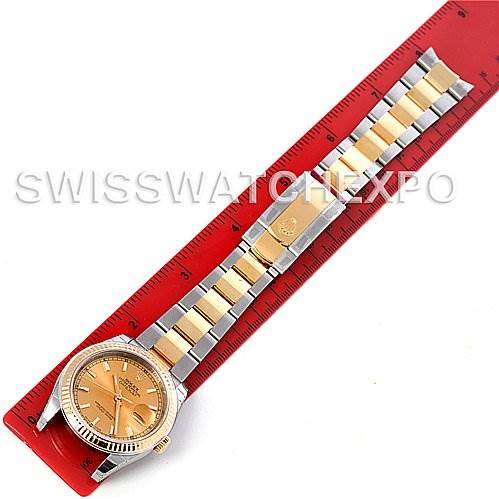 The image shows a top-down view of a Rolex Datejust 116233 Men
s Stainless Steel Champagne Dial 116233 Men
s Stainless Steel Champagne Dial watch, fully extended and placed against a red ruler for scale.