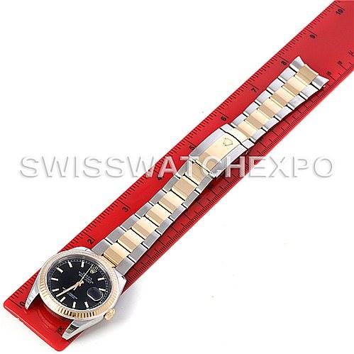 The image shows a Rolex Datejust 116233 Men's Stainless Steel Black Dial 116233 Men's Stainless Steel Black Dial watch laid flat on a red ruler, displaying its face and bracelet.