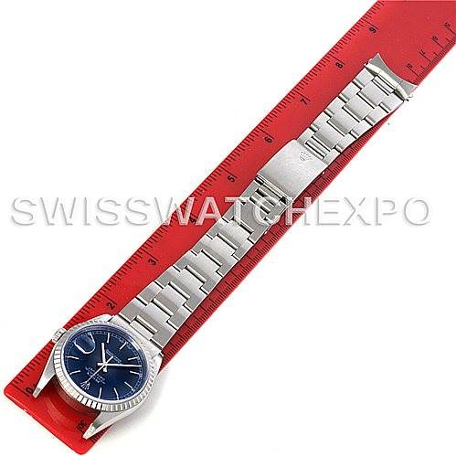 This image shows a Rolex Datejust 16220 Men's Stainless Steel Blue Dial 16220 Men's Stainless Steel Blue Dial watch with a blue dial, laid flat with its bracelet extended alongside a red ruler.
