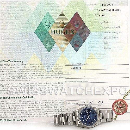 The image shows a Rolex Datejust 16220 Men's Stainless Steel Blue Dial 16220 Men's Stainless Steel Blue Dial model watch placed on its warranty and certification documents.