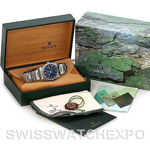 The image shows a Rolex Datejust 16220 Men's Stainless Steel Blue Dial 16220 Men's Stainless Steel Blue Dial watch in an open box with its accessories, including a cleaning cloth, tag, and papers.