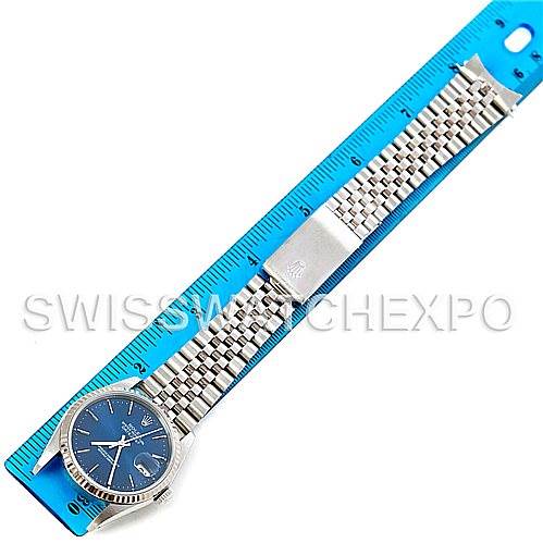 This image shows a Rolex Datejust 16234 Men's Stainless Steel Blue Dial 16234 Men's Stainless Steel Blue Dial watch with a blue dial and stainless steel Jubilee bracelet placed alongside a blue ruler.