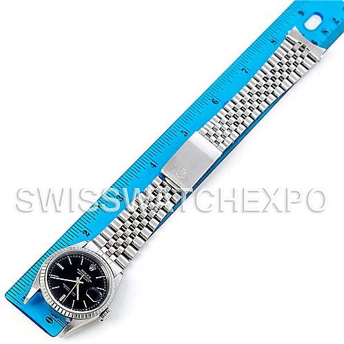 This image shows a top-down view of a Rolex Datejust 16220 Men's Stainless Steel Black Dial 16220 Men's Stainless Steel Black Dial watch with its bracelet extended alongside a ruler.