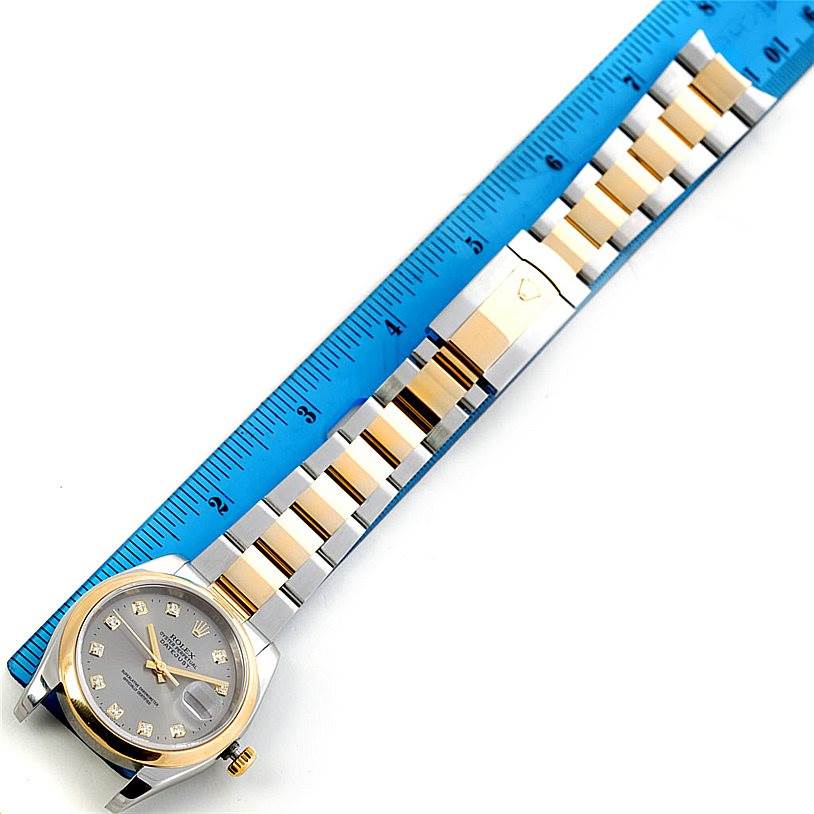 This Rolex Datejust 116203 Men's Stainless Steel Grey Dial 116203 Men's Stainless Steel Grey Dial watch is displayed flat, showcasing its dial, case, and entire two-tone metal bracelet next to a ruler.