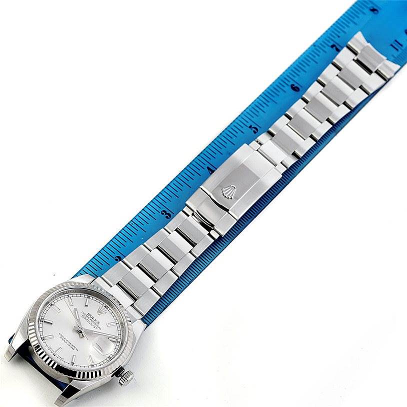 The image shows a top-down view of a Rolex Datejust 116234 Men
s Stainless Steel Silver Dial 116234 Men
s Stainless Steel Silver Dial watch, including the watch face and the band against a ruler.