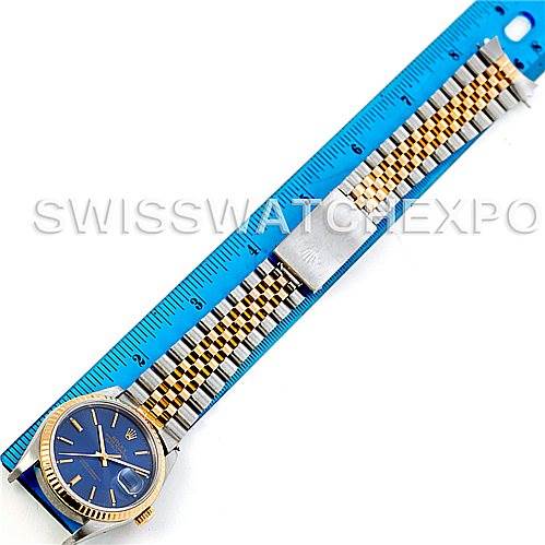 The image shows a Rolex Datejust 16233 Men
s Steel and Gold (two tone) Blue Dial 16233 Men
s Steel and Gold (two tone) Blue Dial watch laid flat with its bracelet fully extended alongside a blue ruler.