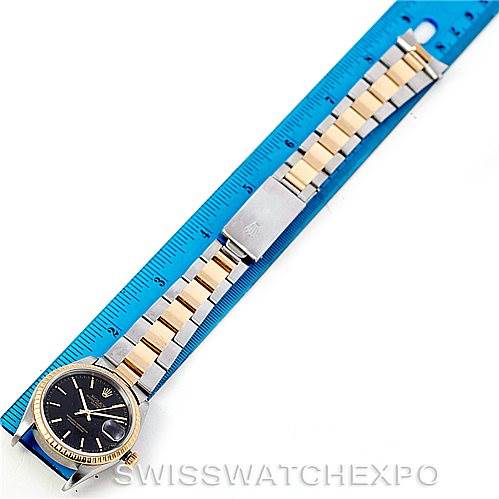 The Rolex Datejust 15223 Men's Steel and Gold (two tone) Black Dial 15223 Men's Steel and Gold (two tone) Black Dial watch is shown flat on a ruler, displaying the dial, bracelet, and clasp in full view.