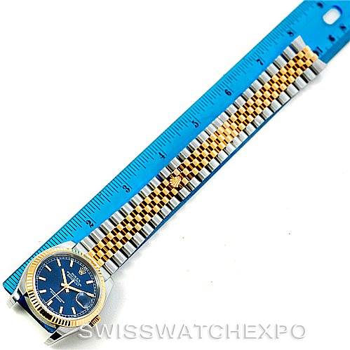 This image shows a Rolex Datejust 116233 Men's Stainless Steel Blue Dial 116233 Men's Stainless Steel Blue Dial watch with a blue dial and two-tone bracelet, placed next to a blue ruler.