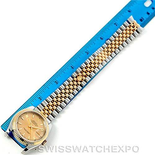 The image shows a Rolex Datejust 116233 Men
s Stainless Steel Champagne Dial 116233 Men
s Stainless Steel Champagne Dial watch laid flat, positioned next to a blue ruler, highlighting its case, bezel, and two-tone bracelet.
