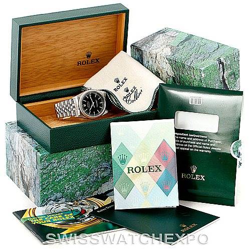 The image shows a Rolex Datejust 16220 Men
s Stainless Steel Black Dial 16220 Men
s Stainless Steel Black Dial watch at an angle inside its green box, along with the outer packaging, manuals, and warranty card.
