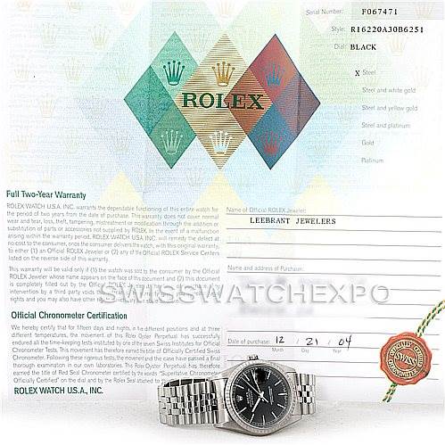 The image shows a Rolex Datejust 16220 Men
s Stainless Steel Black Dial 16220 Men
s Stainless Steel Black Dial watch placed in front of its certificate and warranty paperwork.