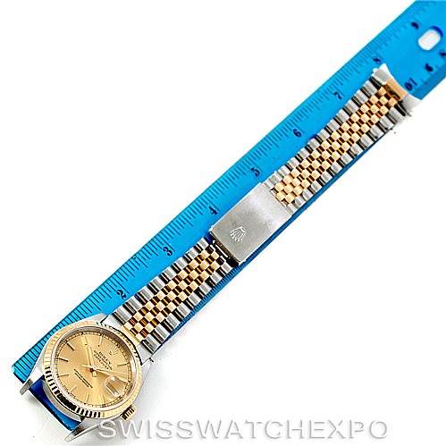 The image shows a Rolex Datejust 16233 Men's Steel and Gold (two tone) Champagne Dial 16233 Men's Steel and Gold (two tone) Champagne Dial watch laid flat alongside a blue ruler, displaying its gold dial and two-tone bracelet.
