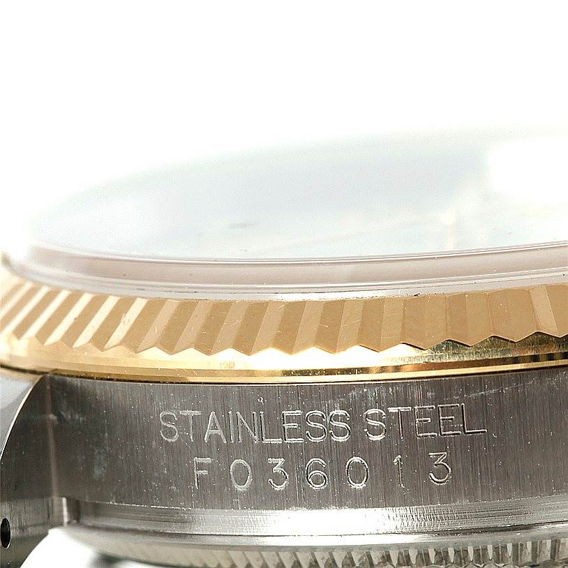 This close-up image shows the side of a Rolex Datejust 116233 Men's Stainless Steel Beige Dial 116233 Men's Stainless Steel Beige Dial watch, highlighting the fluted bezel and stainless steel case with an engraved serial number.