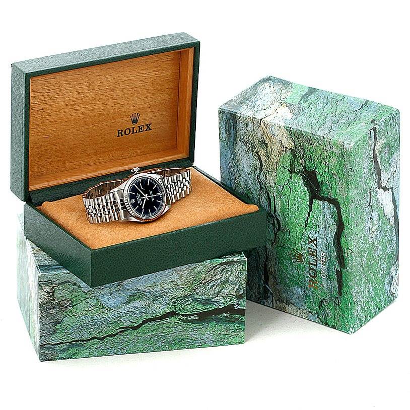 The Rolex Datejust 16220 Men
s Stainless Steel Black Dial 16220 Men
s Stainless Steel Black Dial watch is displayed in its open box, showing the dial and bracelet, with the outer green box beside it.