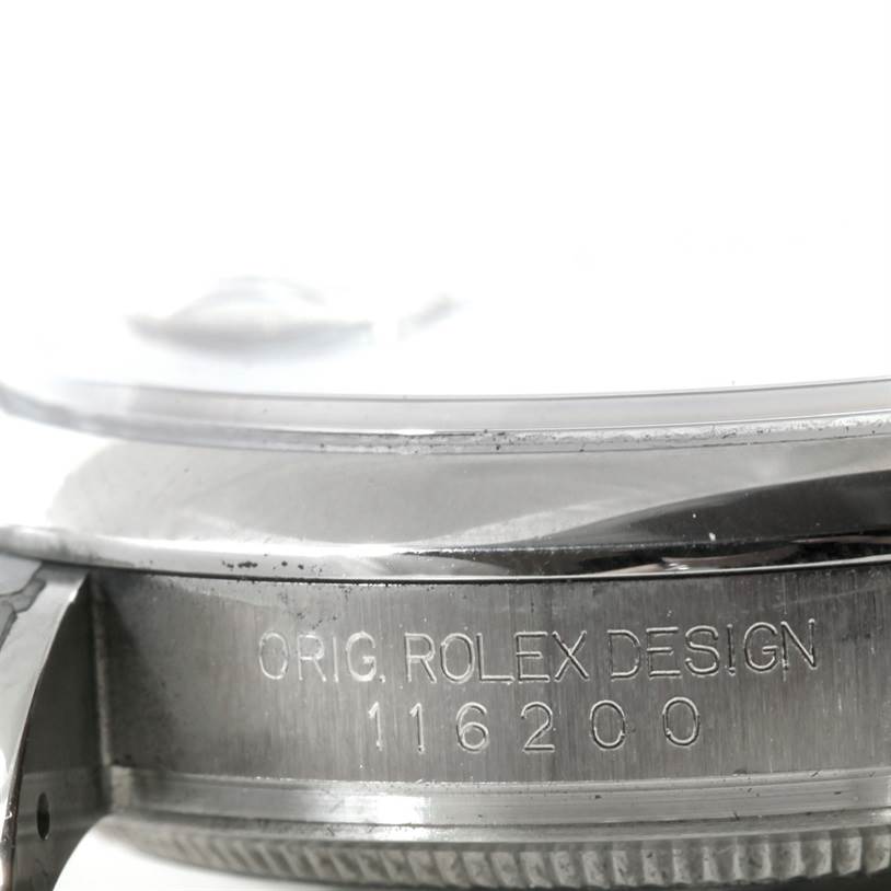 The image shows a close-up of the side of a Rolex Datejust 116200 Men
s Stainless Steel White Dial 116200 Men
s Stainless Steel White Dial watch, featuring the engraved model number "116200."