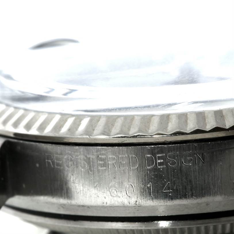 The image shows a close-up side view of the bezel, crystal, and case edge of the Rolex Datejust 16014 Men's Stainless Steel Blue Dial 16014 Men's Stainless Steel Blue Dial watch, with engravings visible.