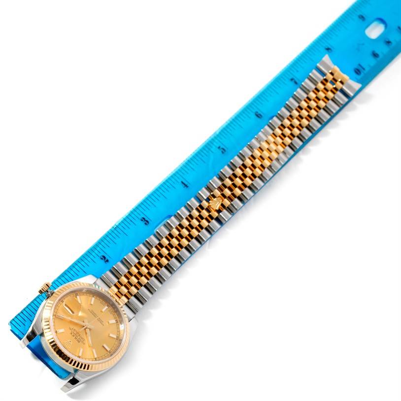 The image shows a Rolex Datejust 116233 Men
s Stainless Steel Champagne Dial 116233 Men
s Stainless Steel Champagne Dial watch laid flat next to a blue ruler, displaying its case, dial, and two-tone bracelet.