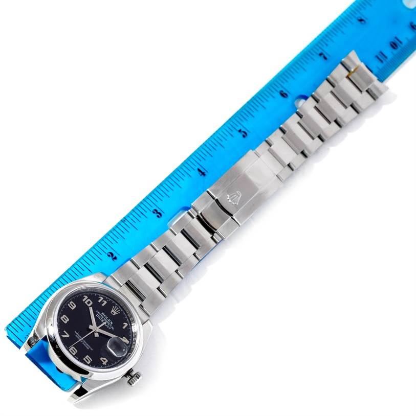 The Rolex Datejust 116200 Men
s Stainless Steel Black Dial 116200 Men
s Stainless Steel Black Dial watch is shown from a top view, highlighting the dial, bracelet, and clasp next to a blue measuring ruler.