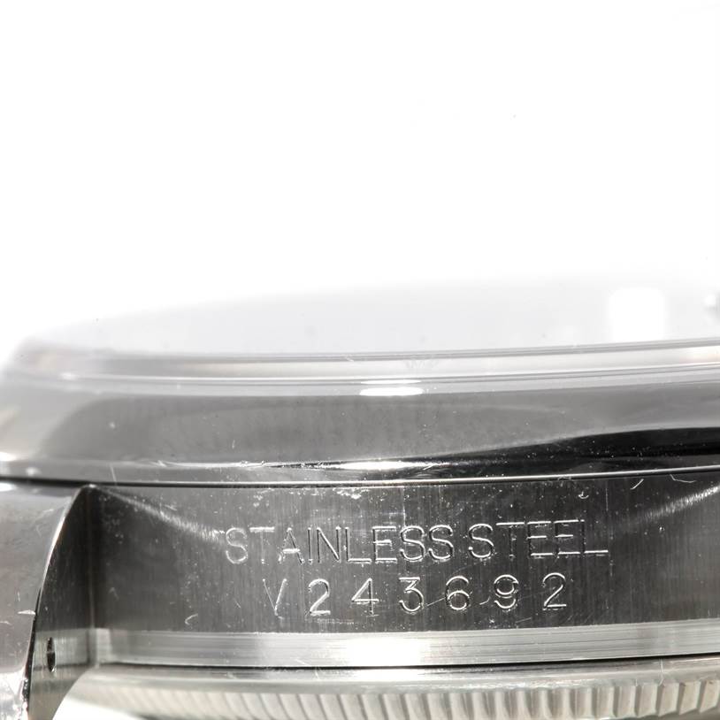 The image shows a close-up of the side of a Rolex Datejust 116200 Men
s Stainless Steel Black Dial 116200 Men
s Stainless Steel Black Dial watch, focusing on its stainless steel case and serial number.