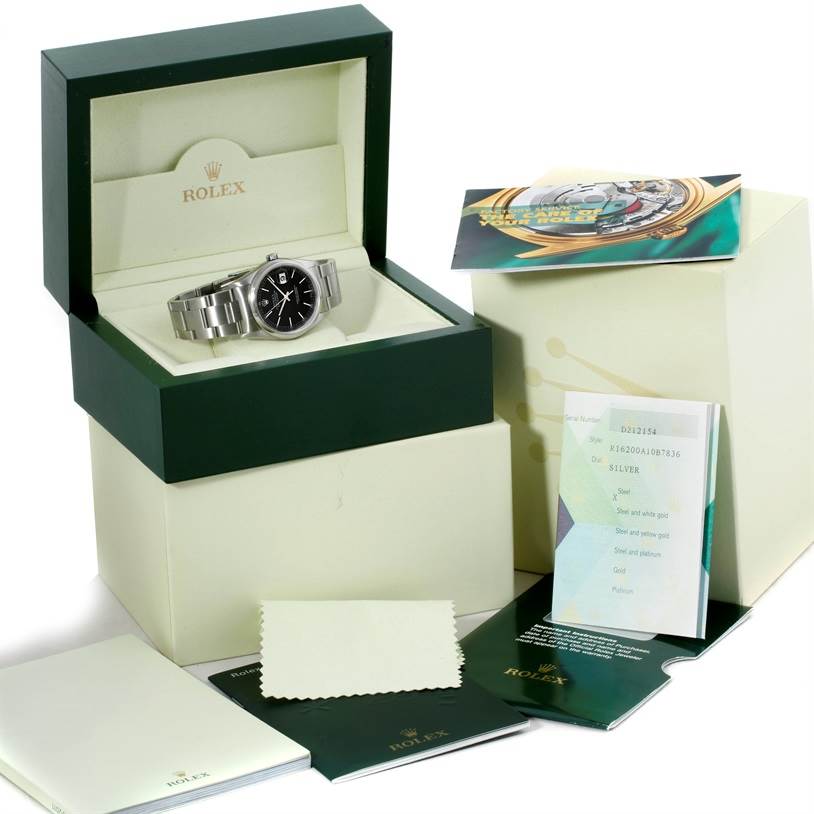 The Rolex Datejust 16200 Men's Stainless Steel Black Dial 16200 Men's Stainless Steel Black Dial watch is displayed in its open box, with manuals, tags, and a cleaning cloth shown around it.