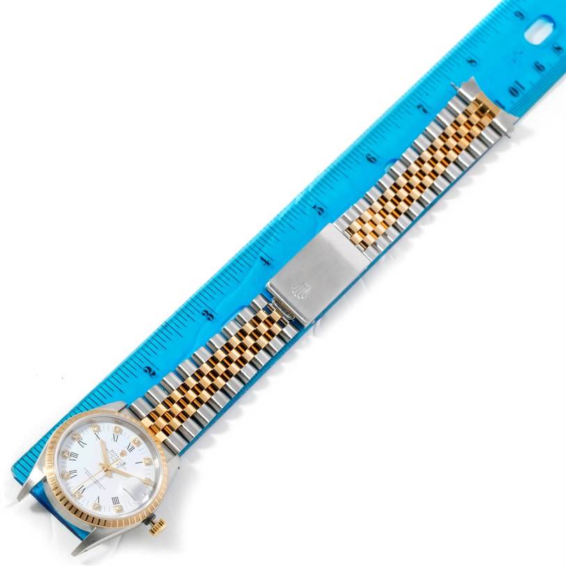 The image shows a Rolex Datejust 15223 Men's Steel and Gold (two tone) White Dial 15223 Men's Steel and Gold (two tone) White Dial watch laid flat alongside a blue ruler, highlighting its dial and jubilee bracelet.