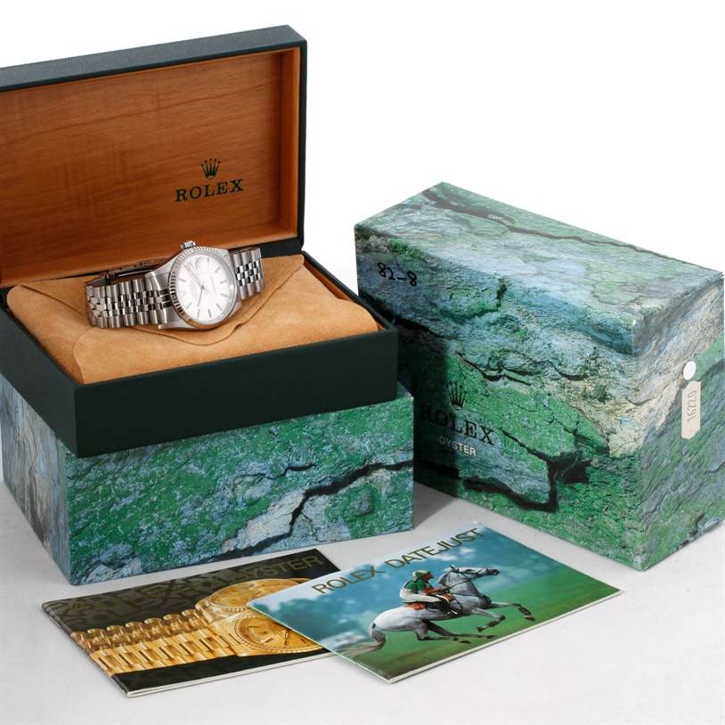 The image shows a Rolex Datejust 16234 Men's Stainless Steel Silver Dial 16234 Men's Stainless Steel Silver Dial watch in an open box, with additional packaging and booklets in the background.