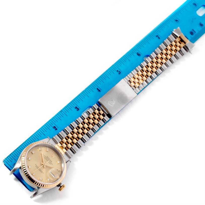 The image shows a top view of a Rolex Datejust 16233 Men's Steel and Gold (two tone) Champagne Dial 16233 Men's Steel and Gold (two tone) Champagne Dial watch with its band aligned next to a blue ruler.