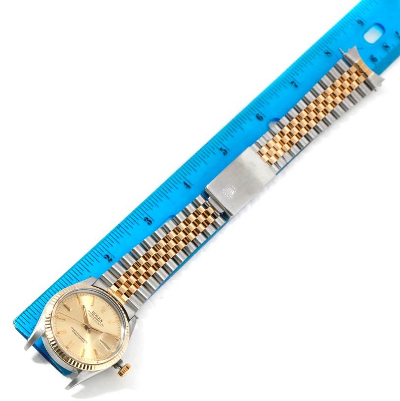 The Rolex Datejust 16013 Men's Stainless Steel Champagne Dial 16013 Men's Stainless Steel Champagne Dial watch is laid flat, showing the face, dial, and two-tone bracelet next to a blue ruler for scale.