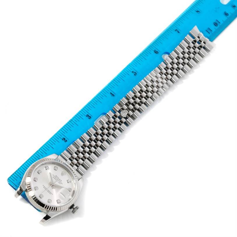 The image shows a Rolex Datejust 116234 Men's Stainless Steel Silver Dial 116234 Men's Stainless Steel Silver Dial watch laid flat with a blue ruler alongside it, displaying the watch face and bracelet.