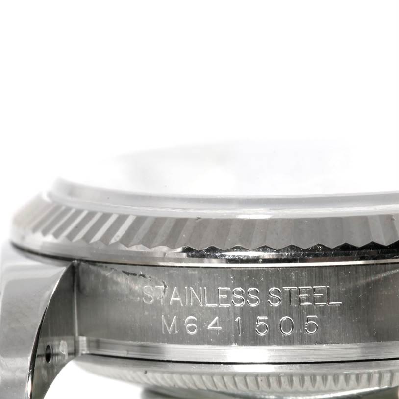 The image shows a close-up side view of the Rolex Datejust 116234 Men's Stainless Steel Silver Dial 116234 Men's Stainless Steel Silver Dial model's bezel and case with engraved serial numbers.